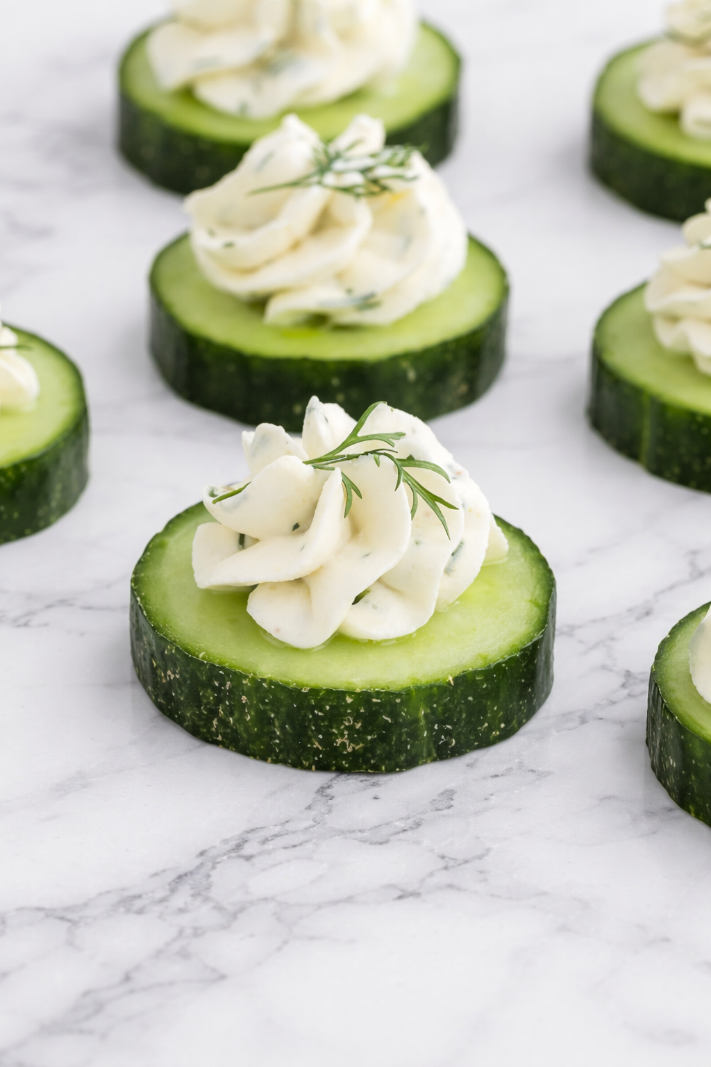 A selection of elegant cucumber cream cheese canapés arranged on a platter, garnished with fresh dill and herbs, ready to serve at a party.