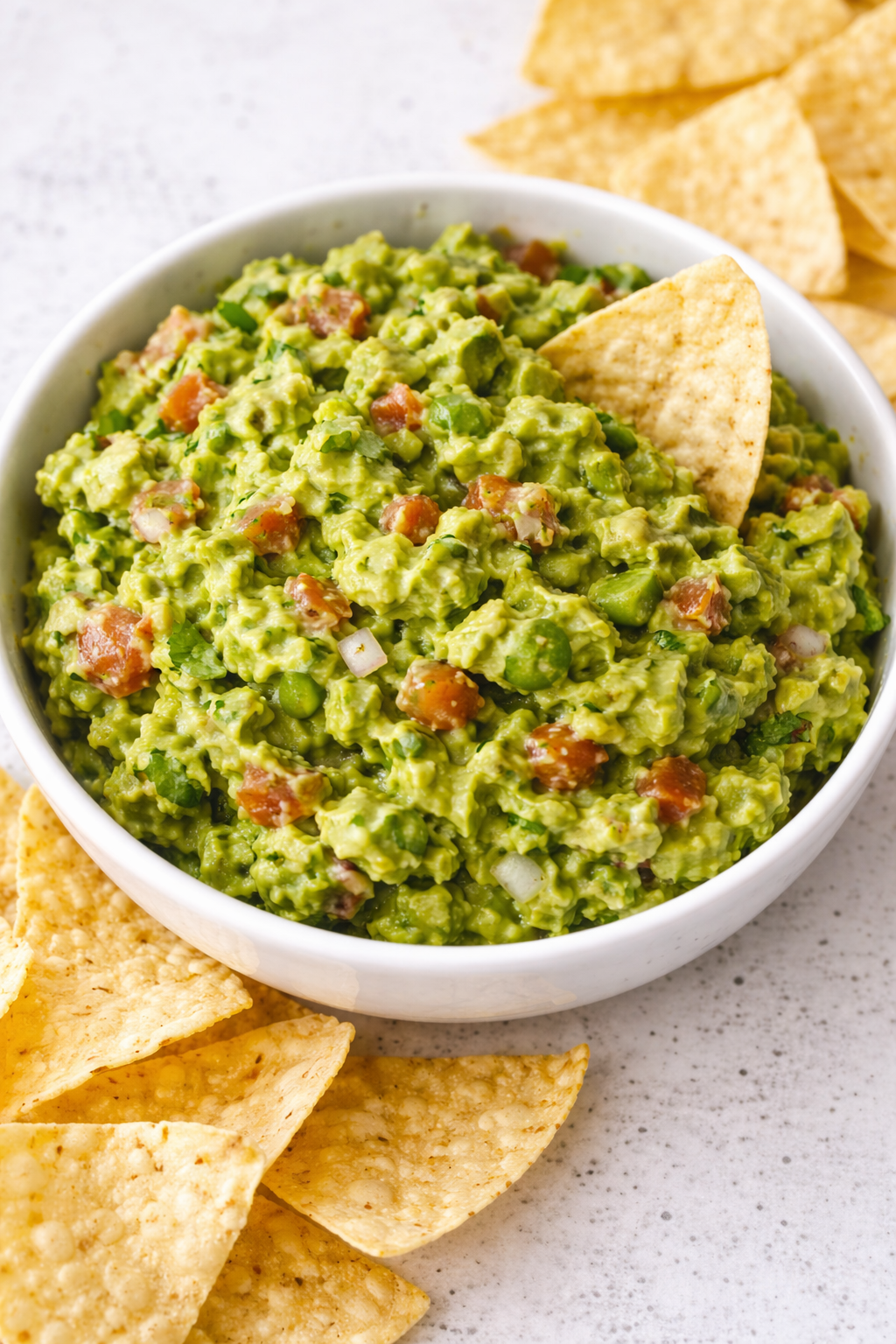 A bowl of fresh guacamole made with ripe avocados, diced tomatoes, minced onion, jalapeño, cilantro, and lime juice — served as a vibrant, creamy dip.
