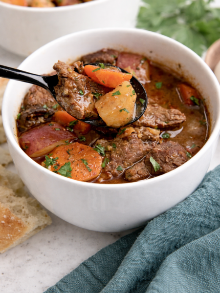 A hearty bowl of Instant Pot Beef Stew filled with tender beef cubes, carrots, potatoes, mushrooms, and pearl onions in a rich broth.
