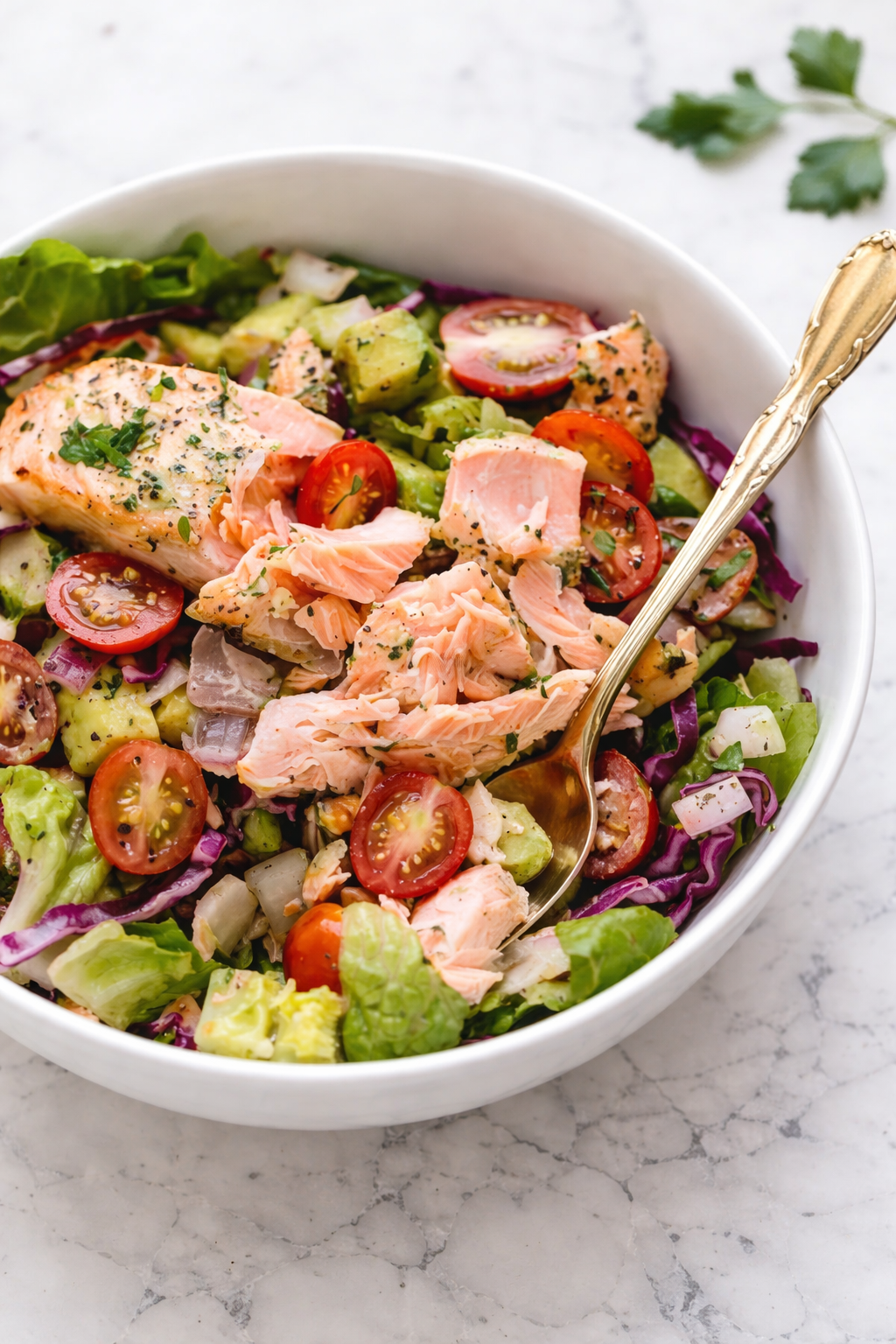 Freshly tossed salmon avocado salad with cherry tomatoes, greens, and lemon vinaigrette