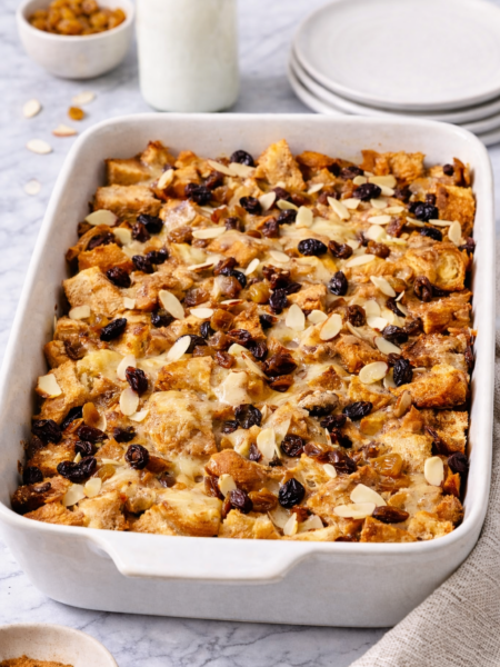 Traditional capirotada made with toasted bread, cinnamon syrup, raisins, nuts, and melted cheese in a baking dish.