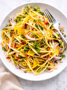 Thai green mango salad with herbs and peanuts in a white bowl