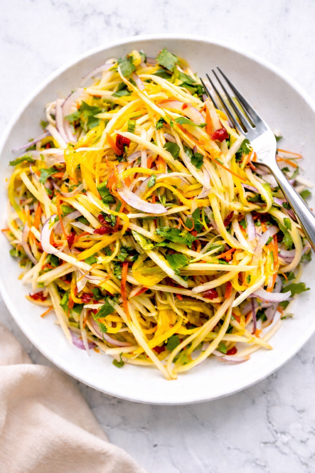 Thai green mango salad with herbs and peanuts in a white bowl