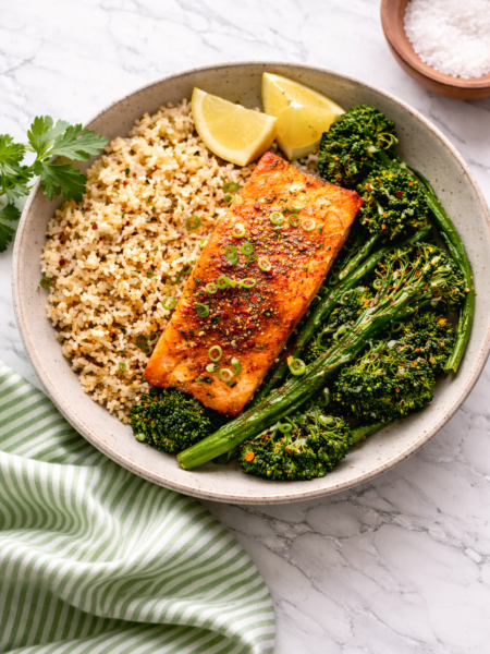 Salmon fillets cooked in an air fryer, seasoned and golden on a white plate.