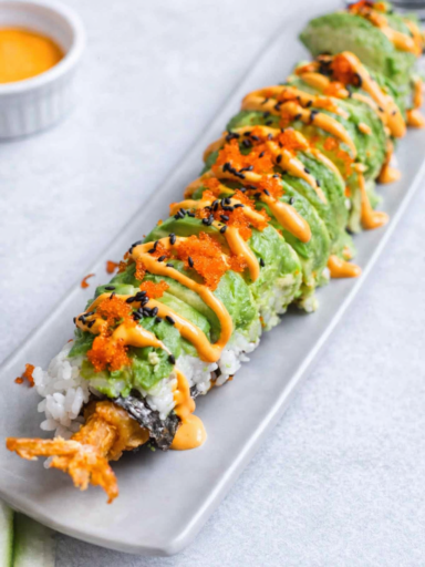 Dragon roll sushi with shrimp tempura, avocado slices, and eel sauce beautifully plated on a sushi board