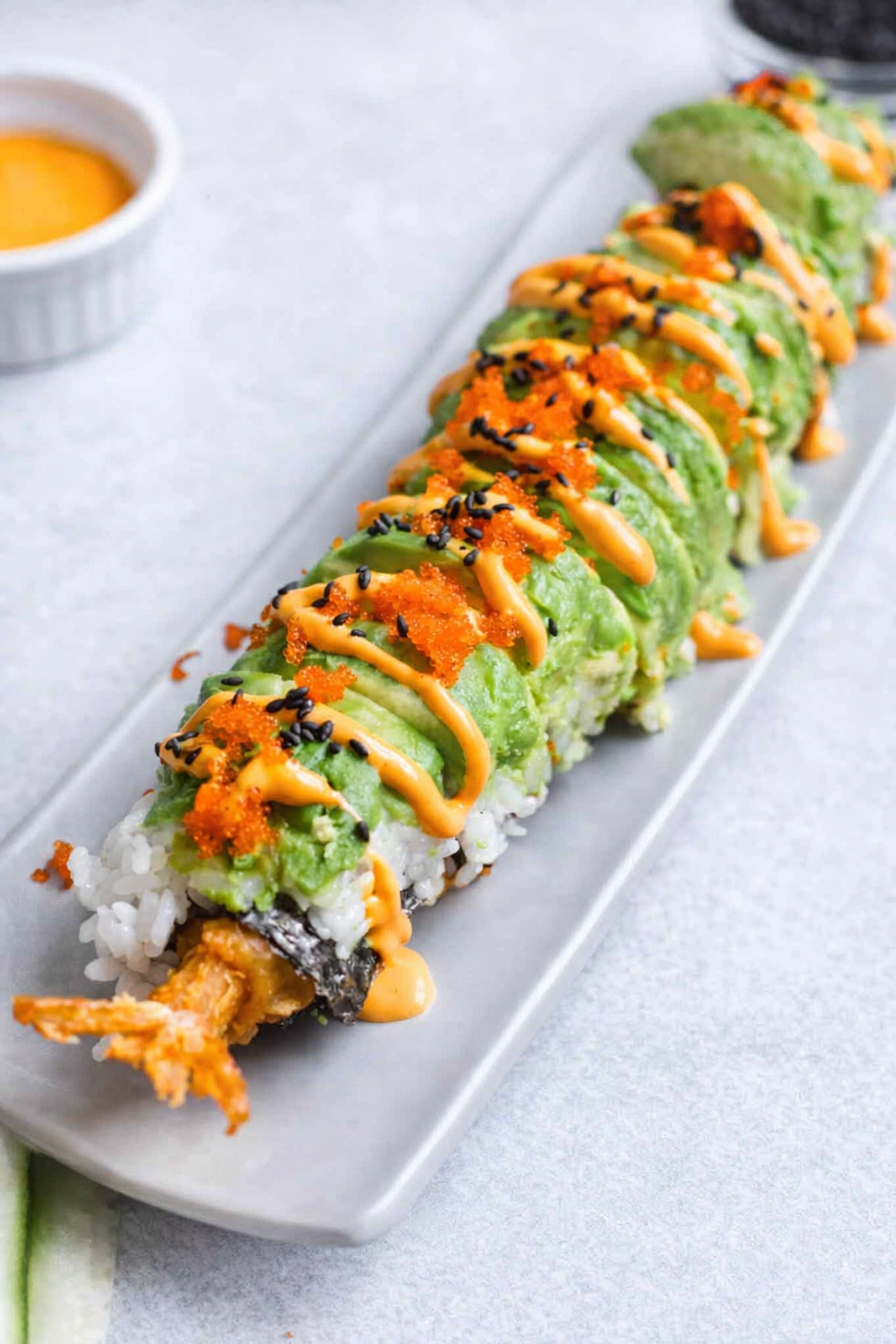 Dragon roll sushi with shrimp tempura, avocado slices, and eel sauce beautifully plated on a sushi board