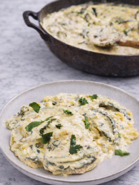 Creamy rajas poblanas con pollo served in a skillet with roasted poblano pepper strips, tender chicken pieces, and a rich velvety sauce, garnished with fresh herbs and vibrant Mexican flavors.