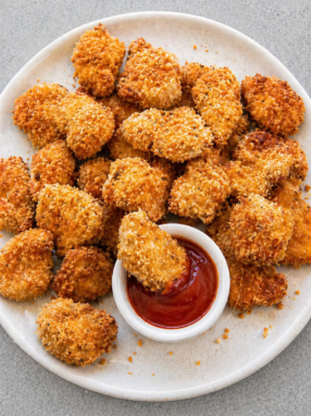 Golden crispy air fryer chicken nuggets served with dipping sauce on a white plate