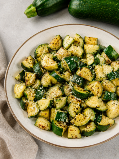 Crispy air fryer zucchini slices served on white plate with herbs