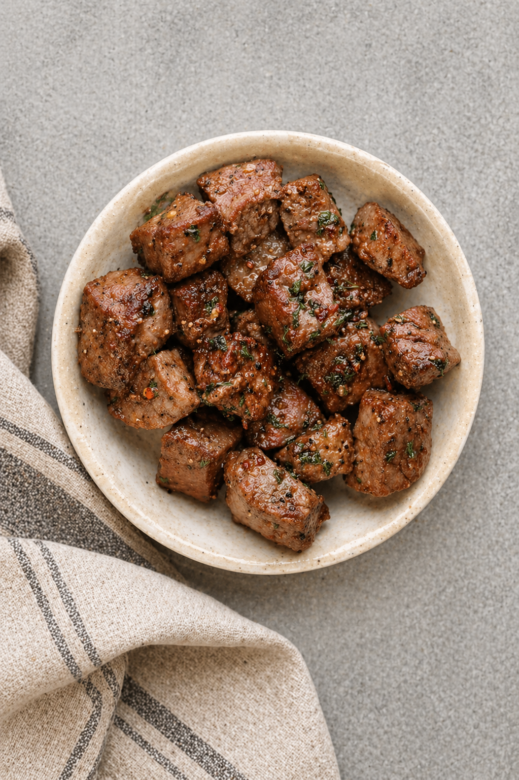 Juicy air fryer steak bites tossed in garlic butter on a white serving plate